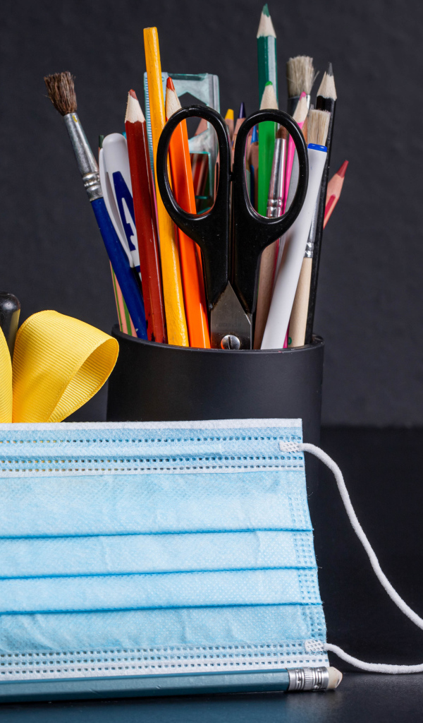 Канцелярские предметы на столе с медицинской маской