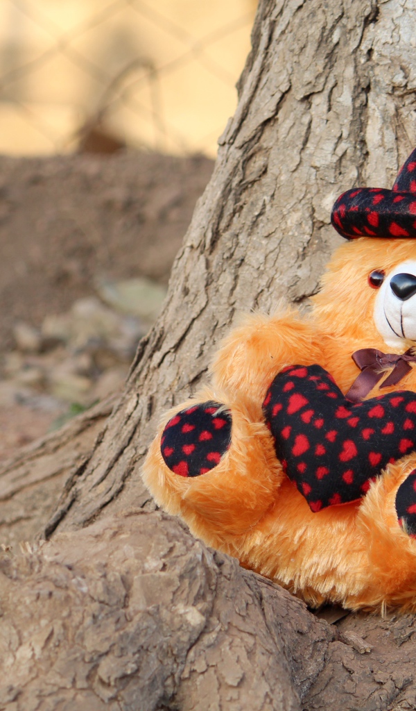 Медвежонок Тедди лежит под деревом