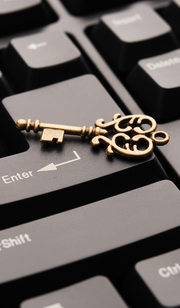 Золотой ключ лежит на черной клавиатуре