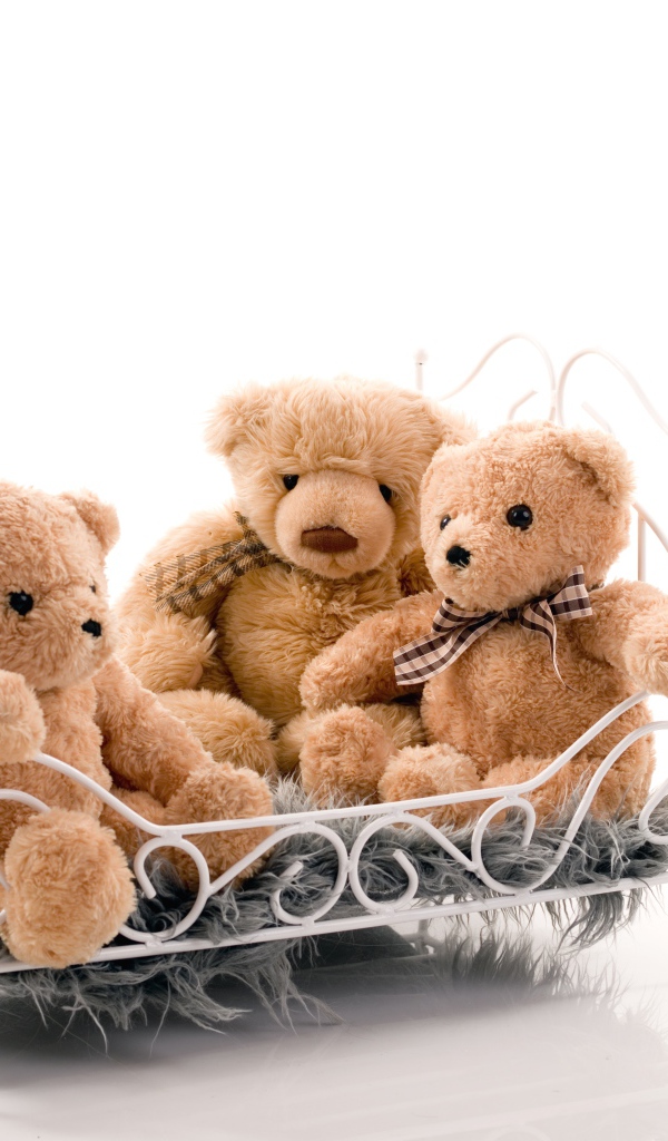 Три игрушечных медведя на кровати на белом фоне