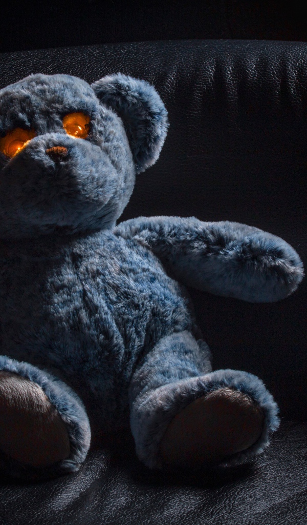 Игрушка со светящимися глазами на черном диване