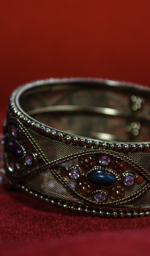 Красивый браслет с драгоценными камнями на красном фоне 