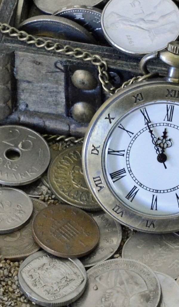 Many coins and pocket watch in the sand