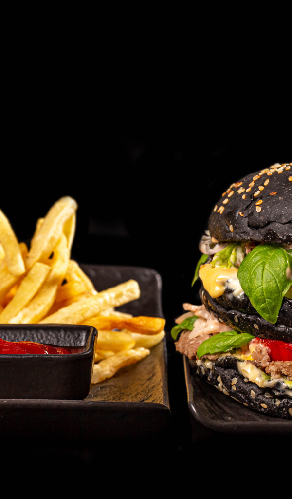 Большой черный гамбургер с картофелем фри и кетчупом 