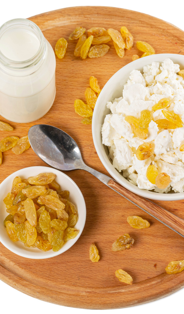 Творог с изюмом и молоком на доске на белом фоне 