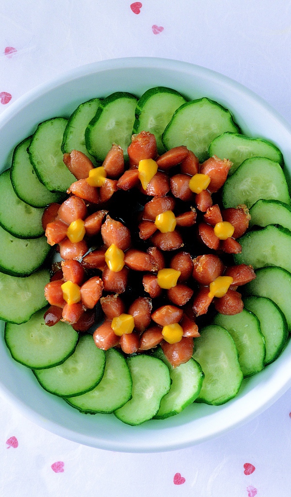 Огурцы с сосисками в тарелке на столе