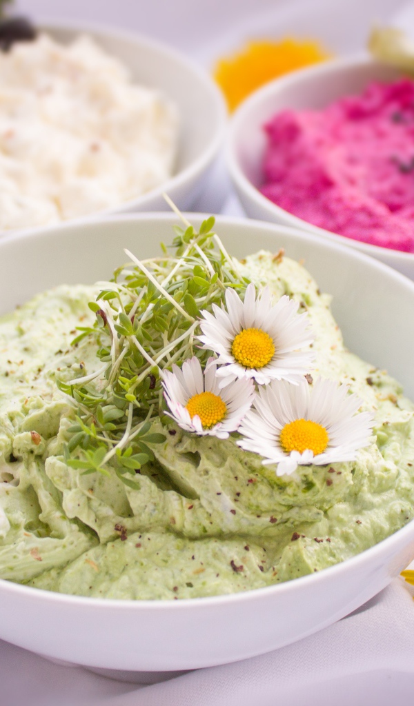 Вкусные салаты в белых мисках на столе с цветами