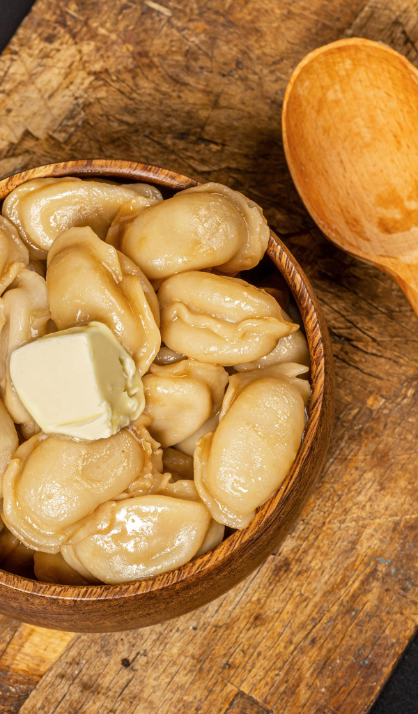 Пельмени в деревянной миске с маслом