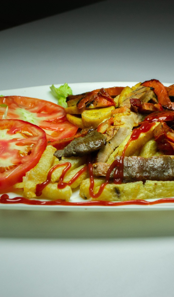 Картофель фри на тарелке с помидорами 