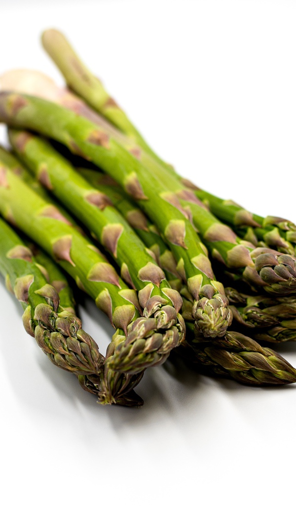 Свежая зеленая спаржа на белом столе