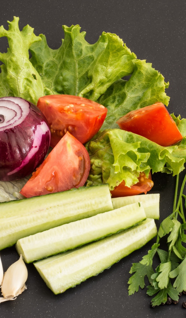 Свежие помидоры, огурцы, лук и листья салата 