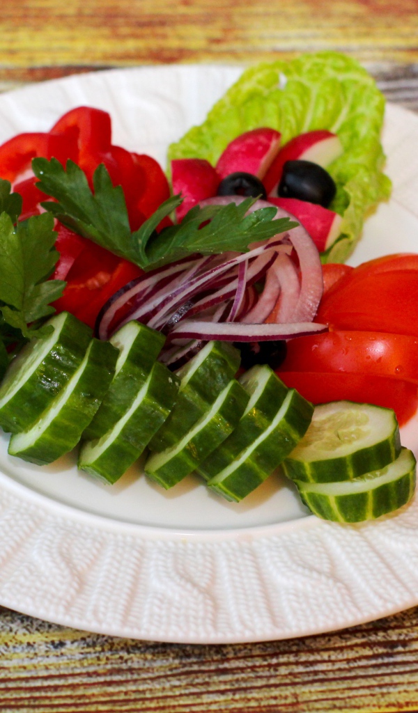 Свежие овощи на белой тарелке на деревянном фоне