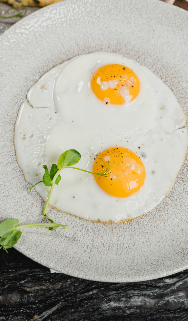 Яичница глазунья на большой серой тарелке