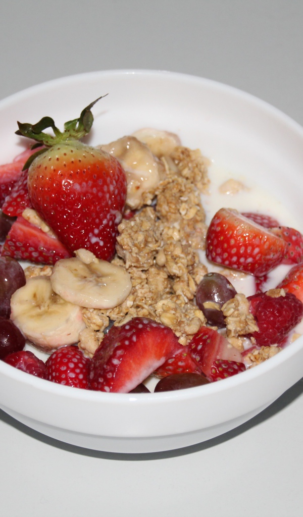 Мюсли с молоком и ягодами на сером столе