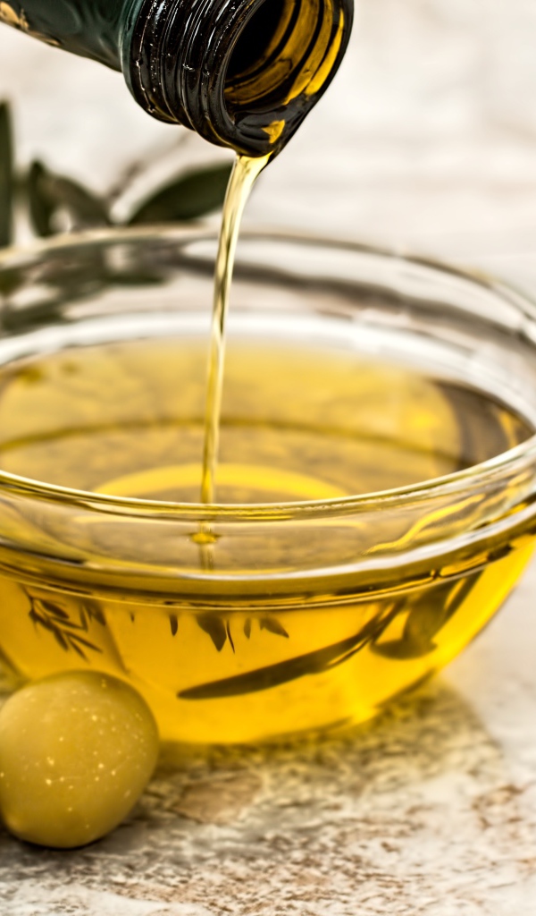 Оливковое масло с оливками на столе 