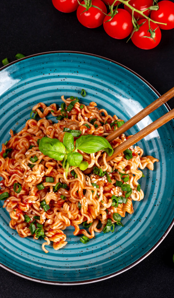 Макароны в соусе на столе с помидорами