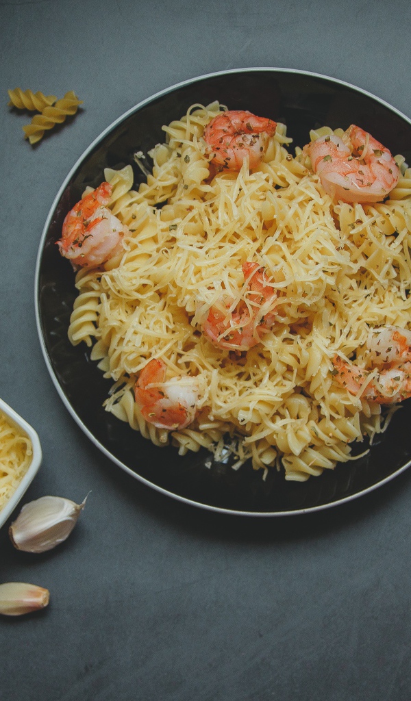 Макароны на тарелке с сыром и креветками