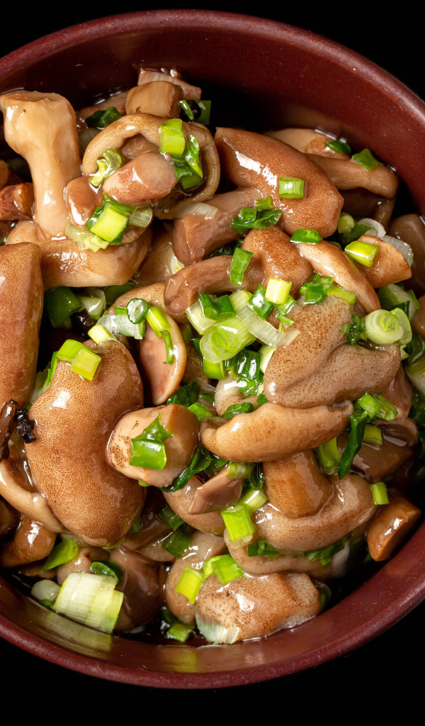 Маринованные маслята с зеленью в тарелке