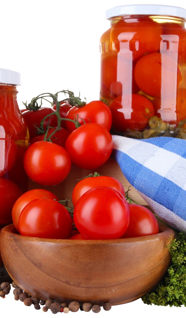 Маринованные помидоры в банках на столе со свежими