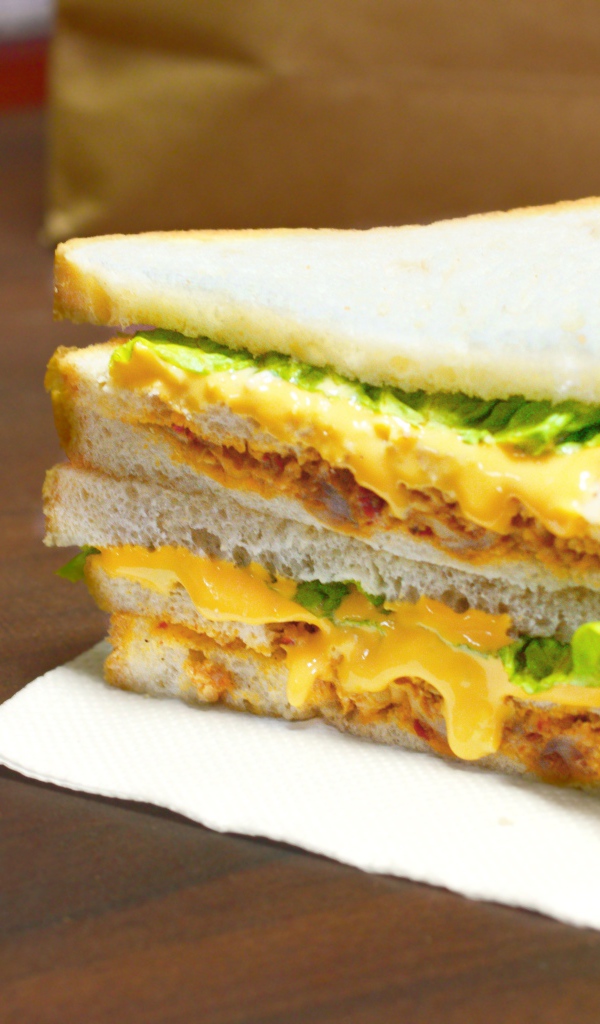 Сэндвич с сыром и листьями салата на столе