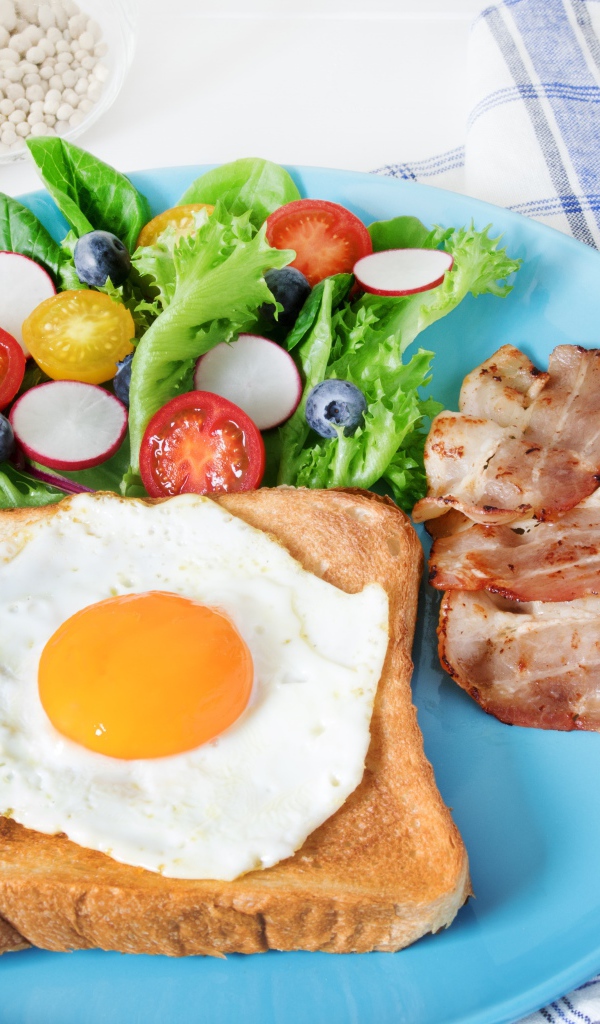 Яичница с хлебом на тарелке с салатом и беконом 