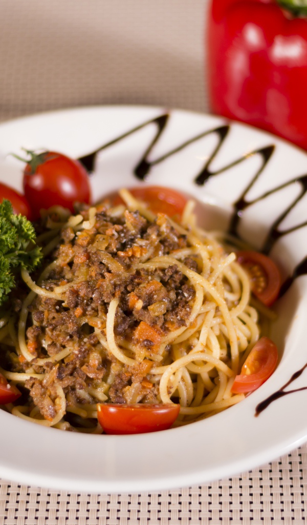 Спагетти с фаршем и помидорами в тарелке 
