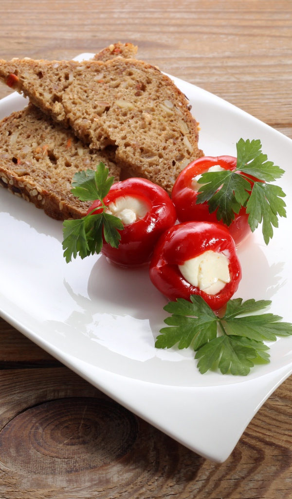 Фаршированный перец на большой белой тарелке с хлебом