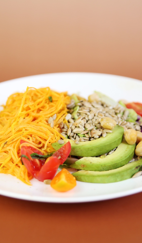 Овощи в белой тарелке на оранжевом фоне 