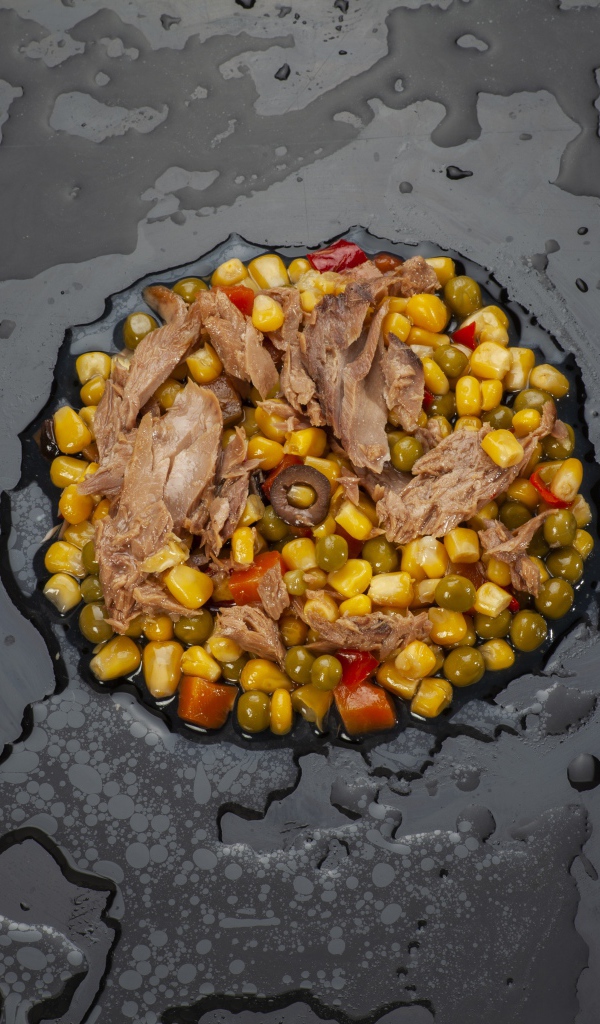 Овощи с мясом и столовыми приборами на черной поверхности