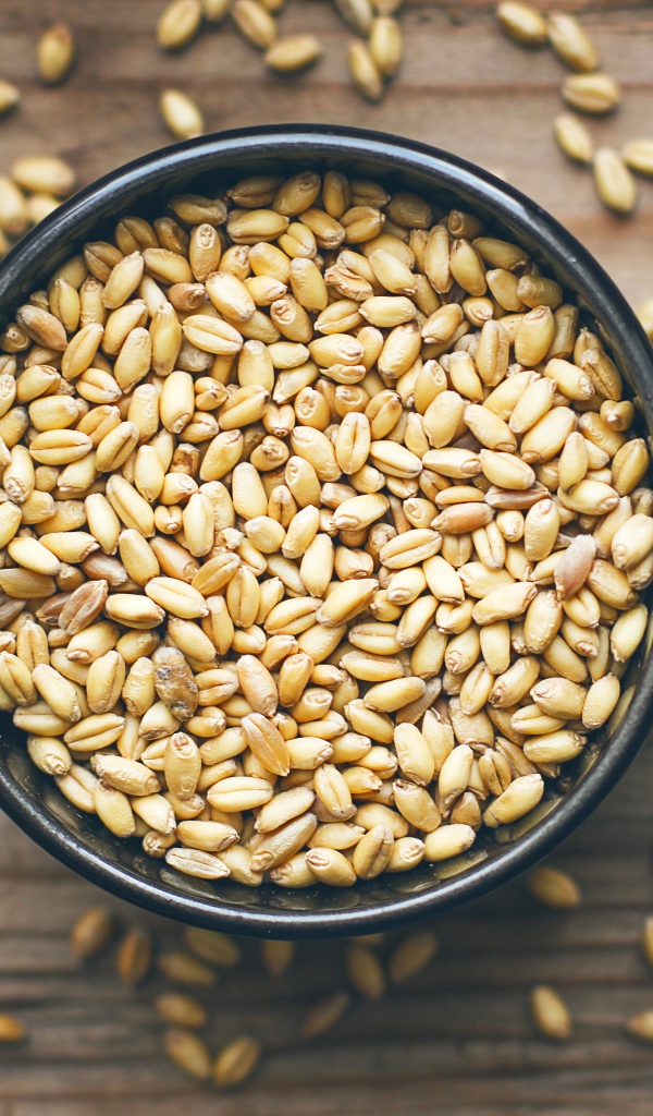 Зерна пшеницы в черной кружке на столе 