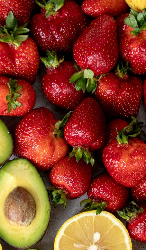 Авокадо, клубника,лимон и груша на сером столе 