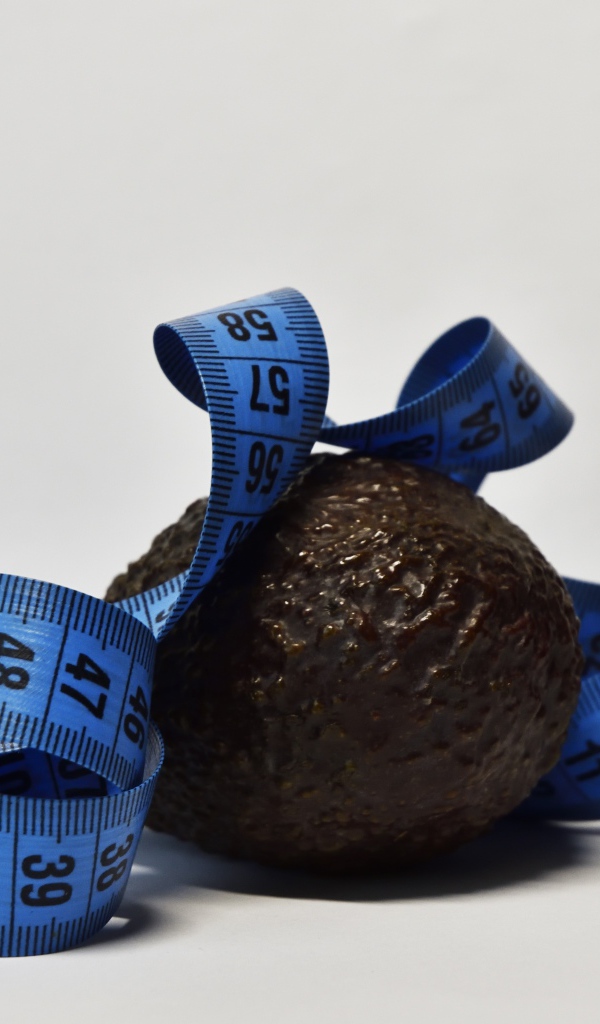 Авокадо с сантиметром на сером фоне