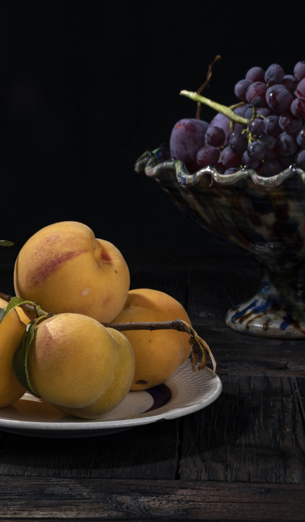 Красивые сочные персики на столе с виноградом