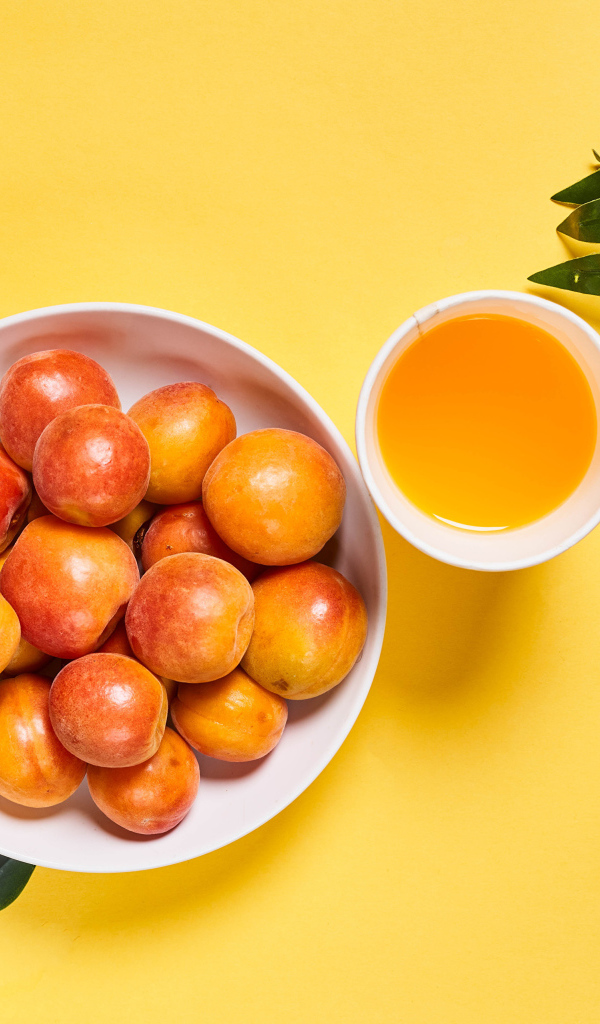 Вкусные спелые абрикосы с зелеными листьями на желтом фоне