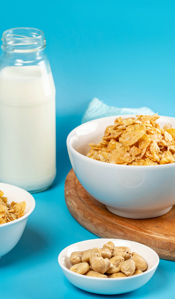 Хлопья на столе с орехами и молоком на голубом фоне