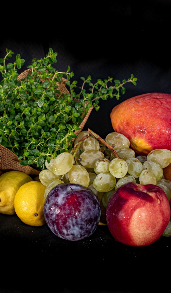 Свежие фрукты с зеленью на черном фоне 