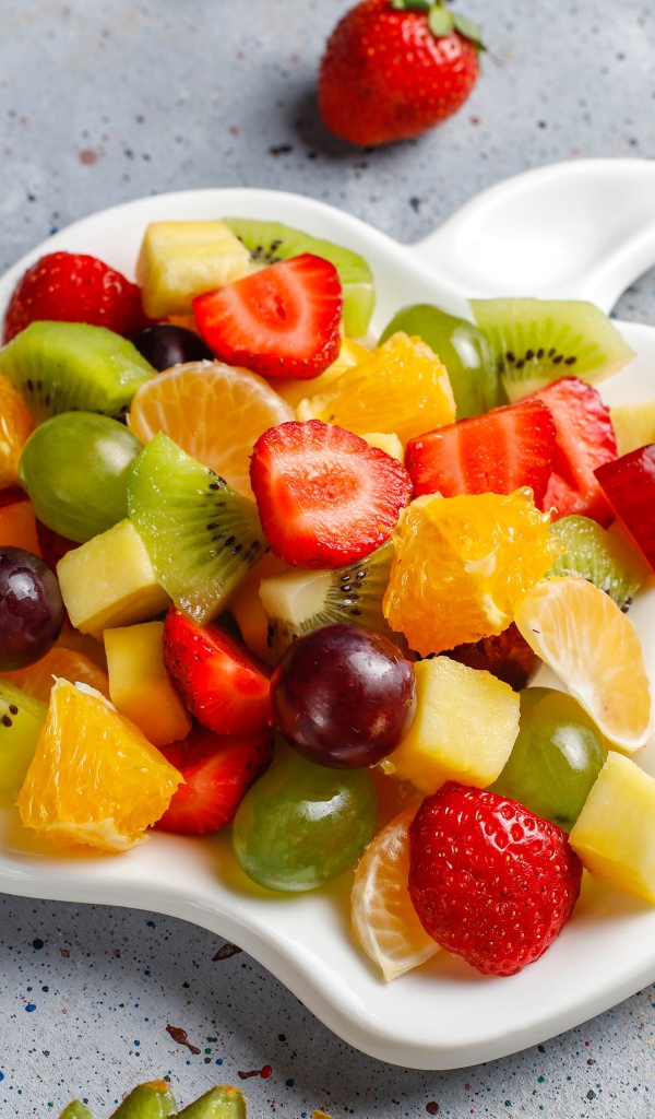 Фруктовый салат на белой тарелке на столе 