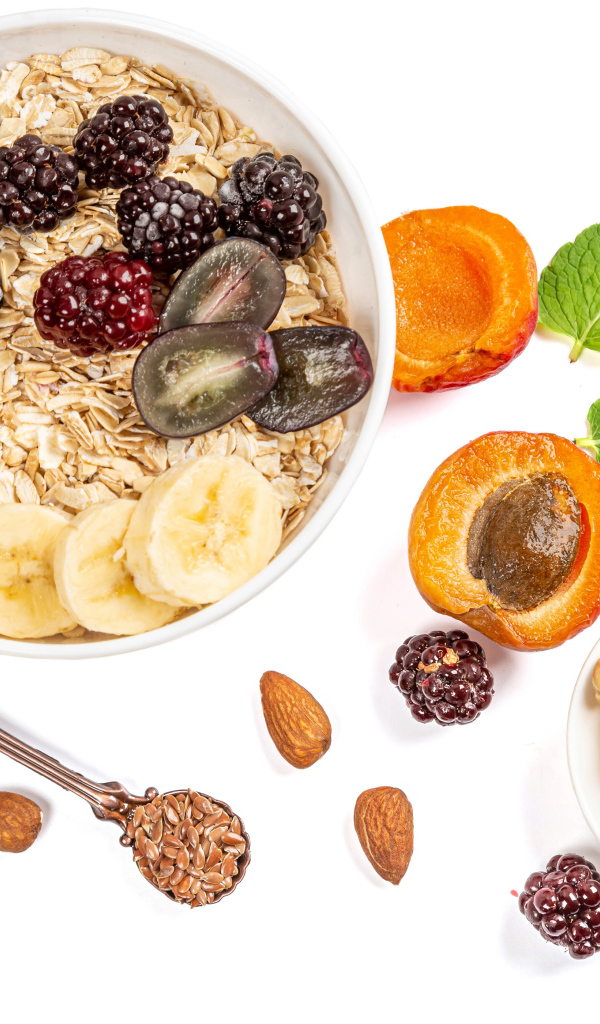 Овсяные хлопья с ягодами и орехами на белом фоне