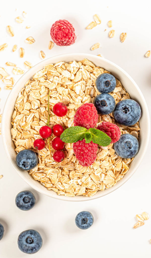 Овсяные хлопья с ягодами черники и малины на белом фоне 