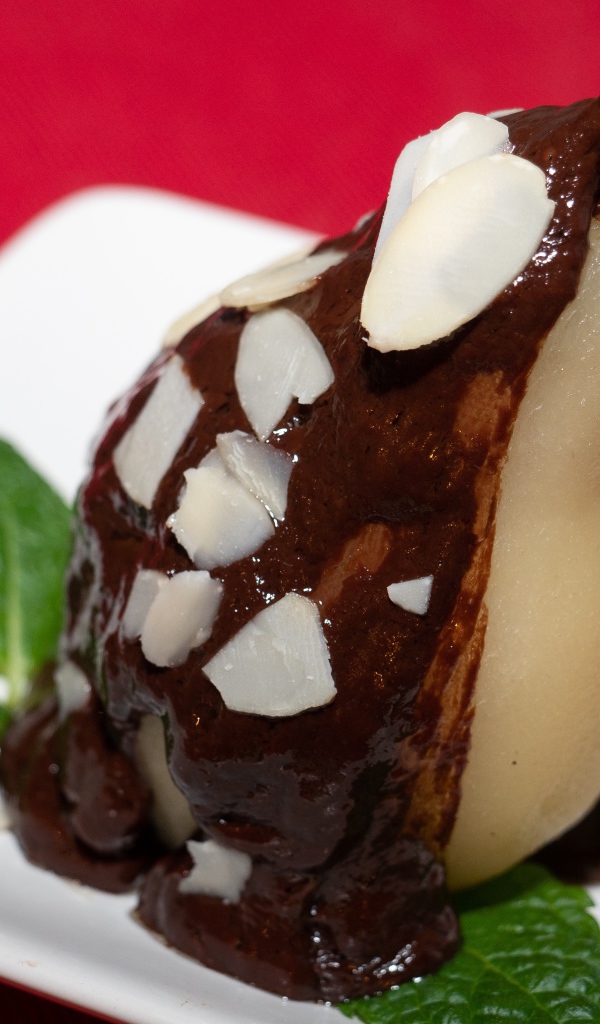 Pear on a white plate with chocolate on a red background