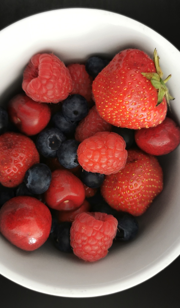 Спелые свежие ягоды в белой тарелке на белом фоне