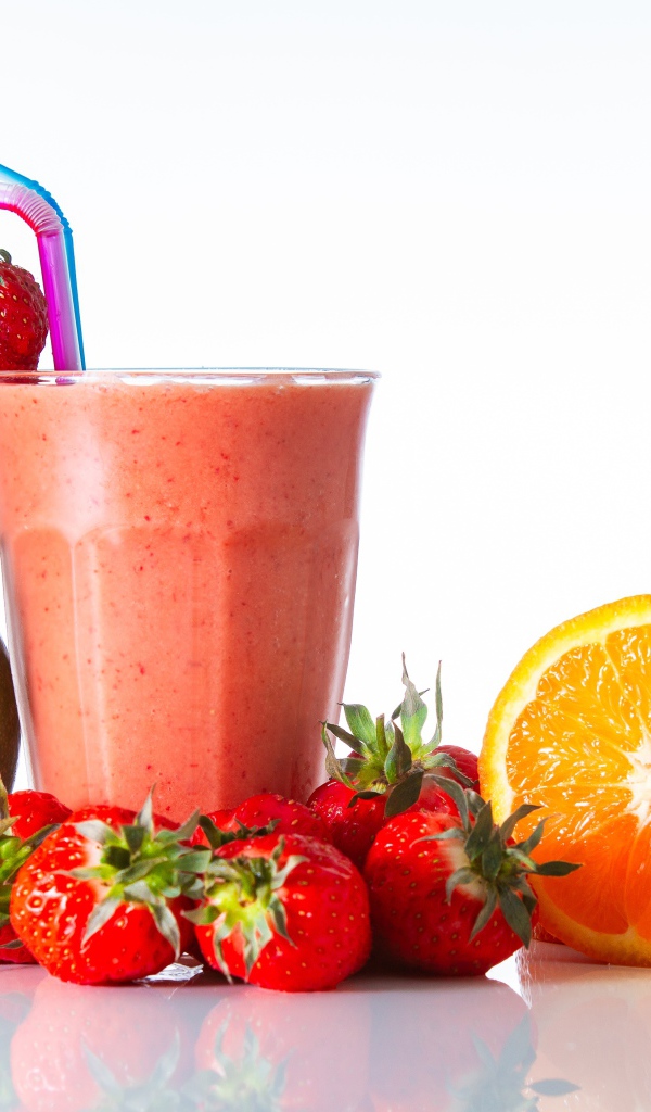 Спелое манго с клубникой и апельсином на столе со смузи