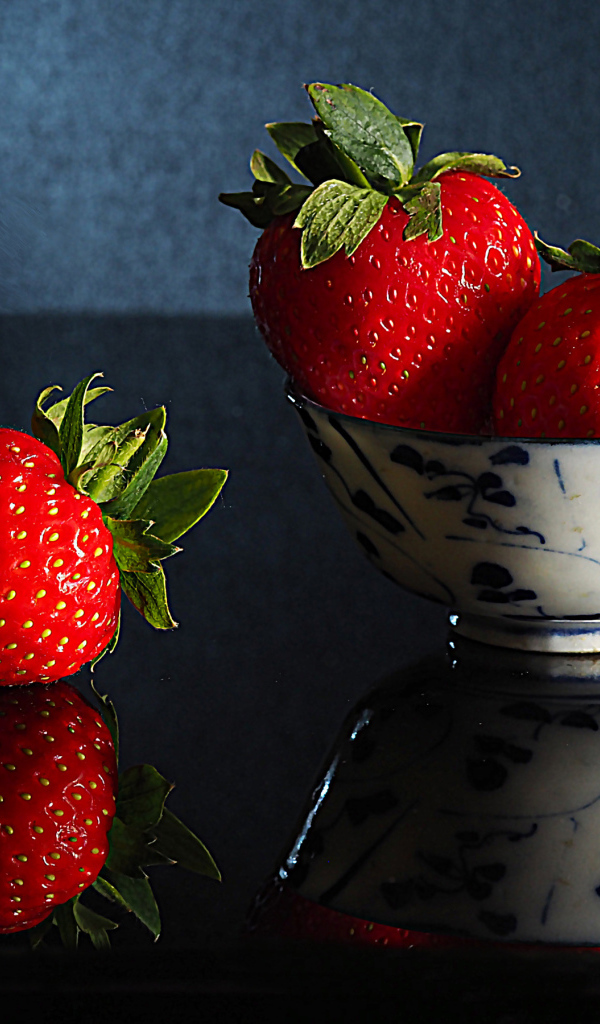 Три красные клубники в миске на столе