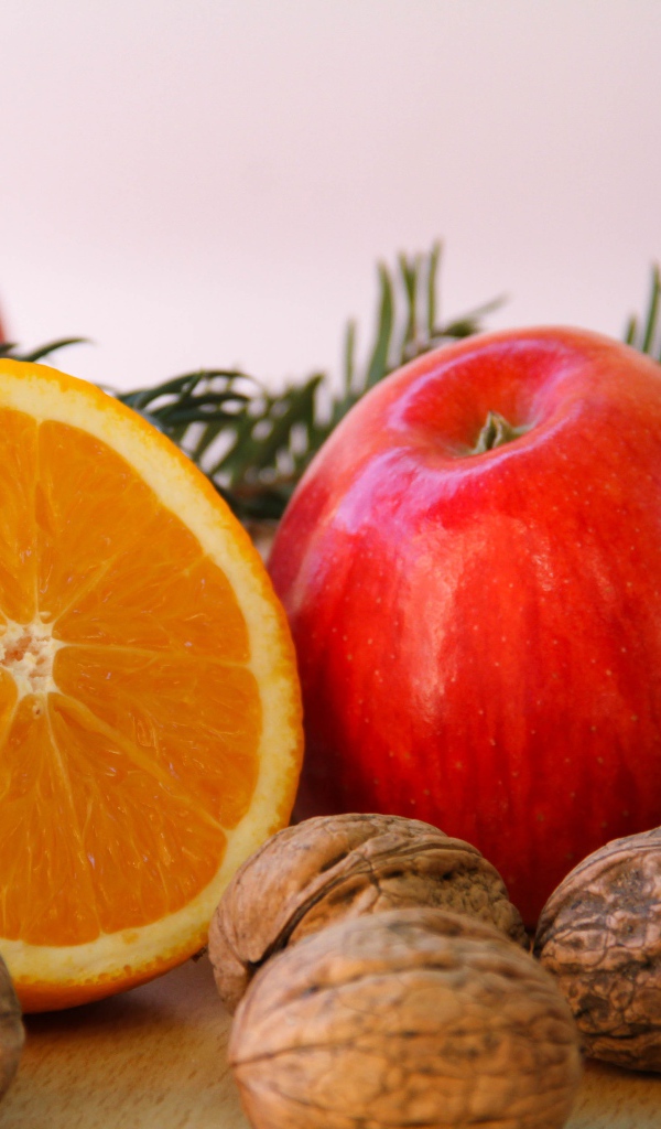 Грецкие орехи с апельсинами и яблоками на сером фоне 