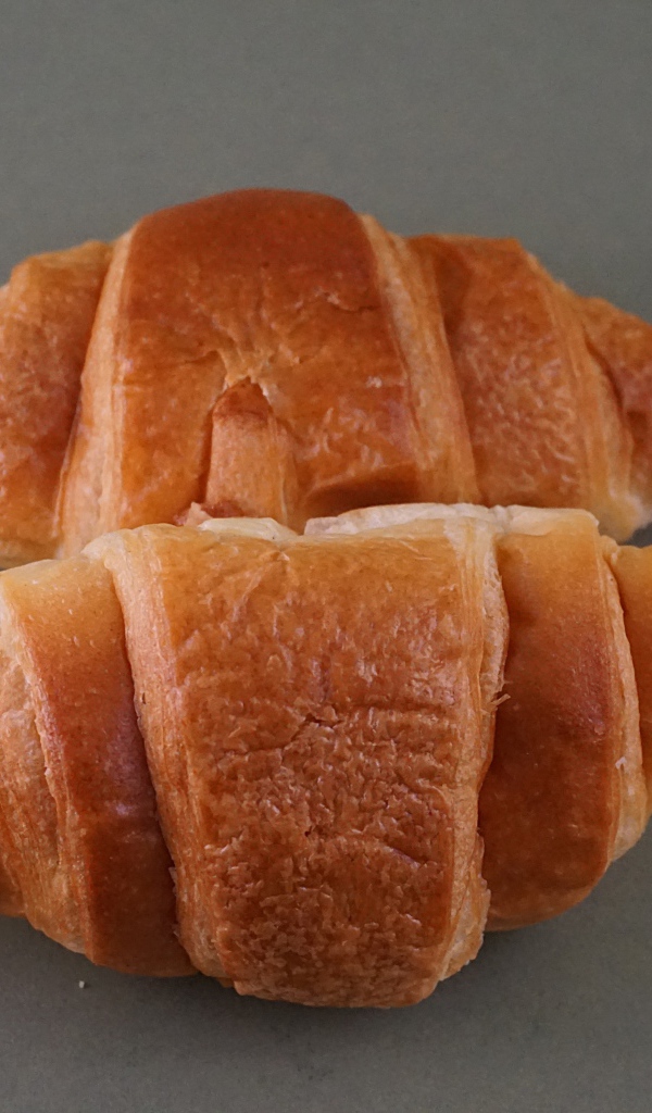 Два свежих круассана на серой поверхности