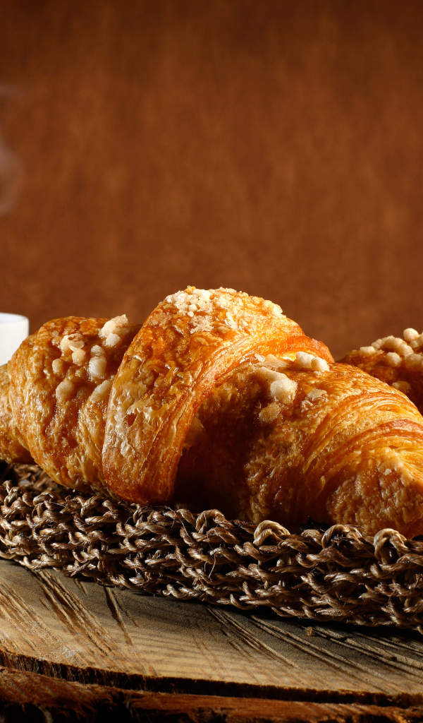 Два свежих круассана на столе с кофе 