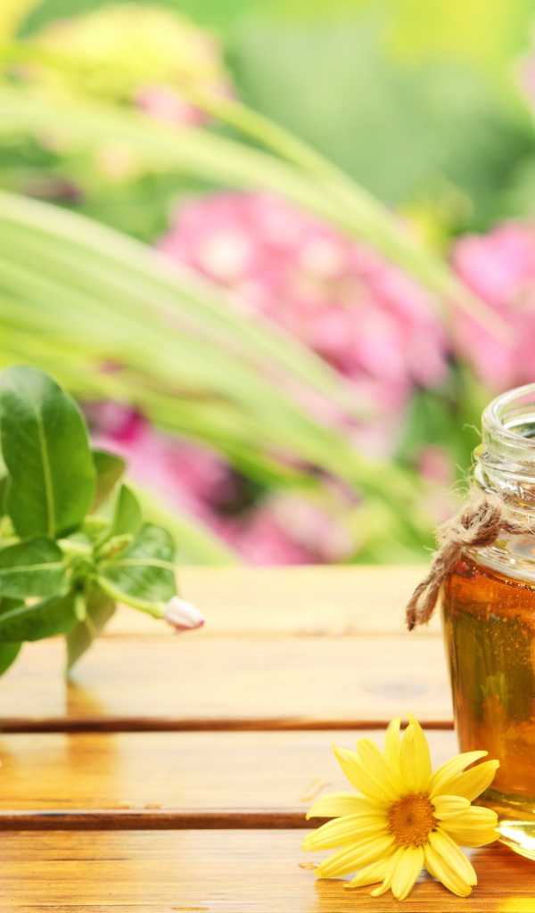 Банка ароматного меда на столе с цветами