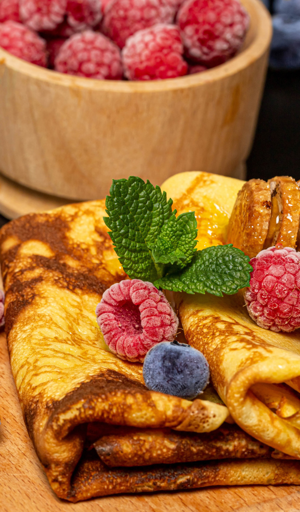 Аппетитные блины с малиной и черникой на столе