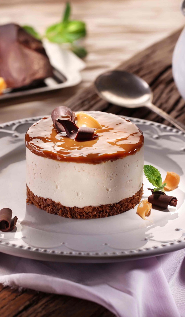 Пирожное на большой круглой тарелке на столе с шоколадом