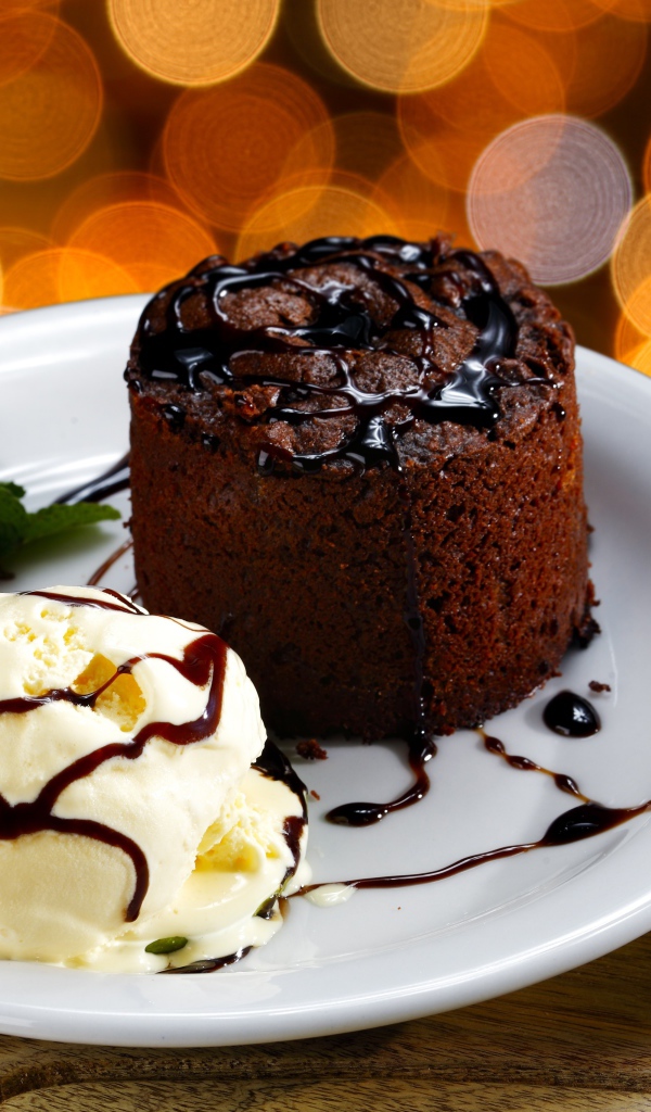 Шоколадный десерт с мороженым и клубникой на белой тарелке 